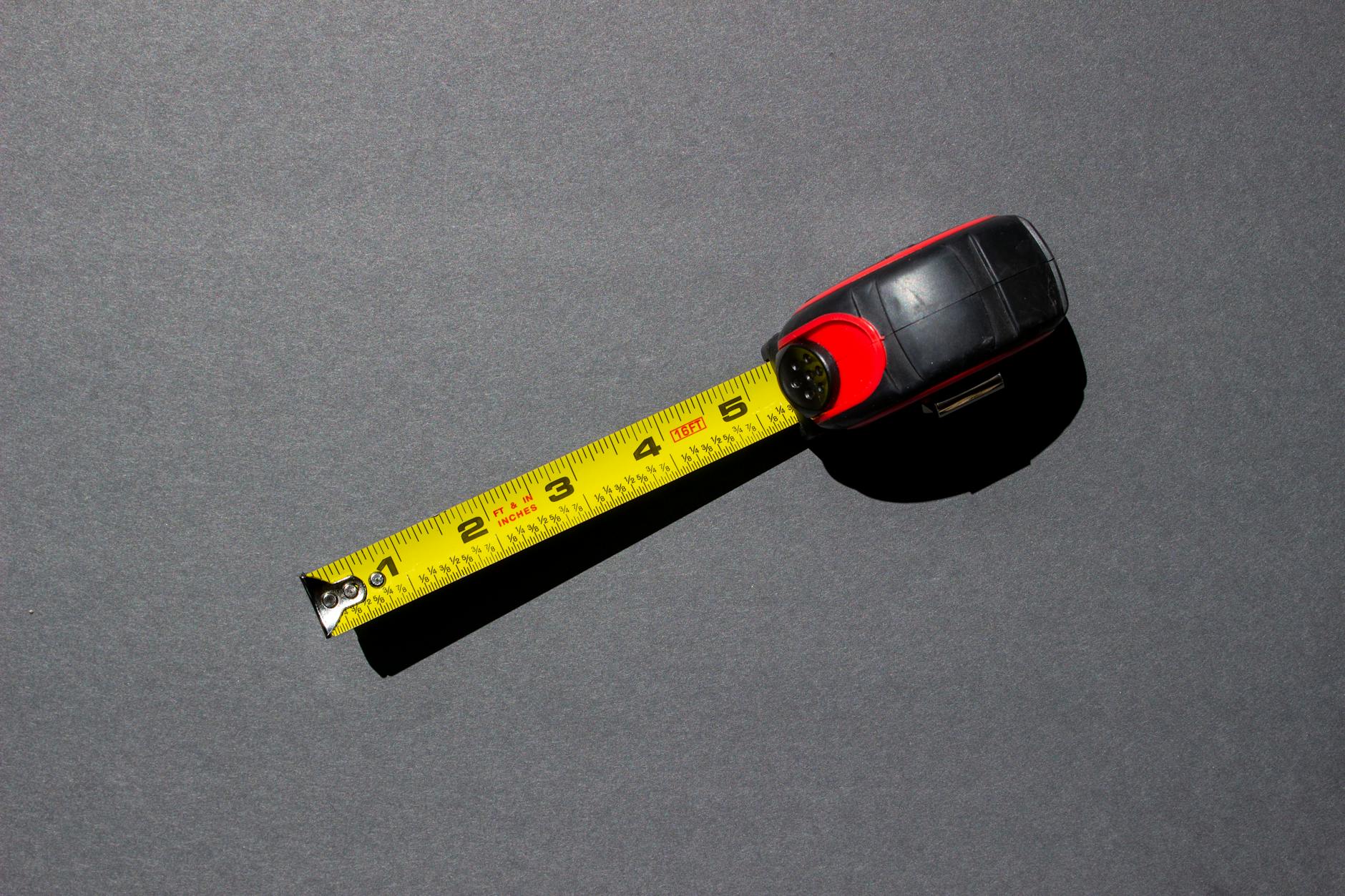 Hands using a cloth measuring tape to measure the main beam of a mule deer rack on a scoring sheet